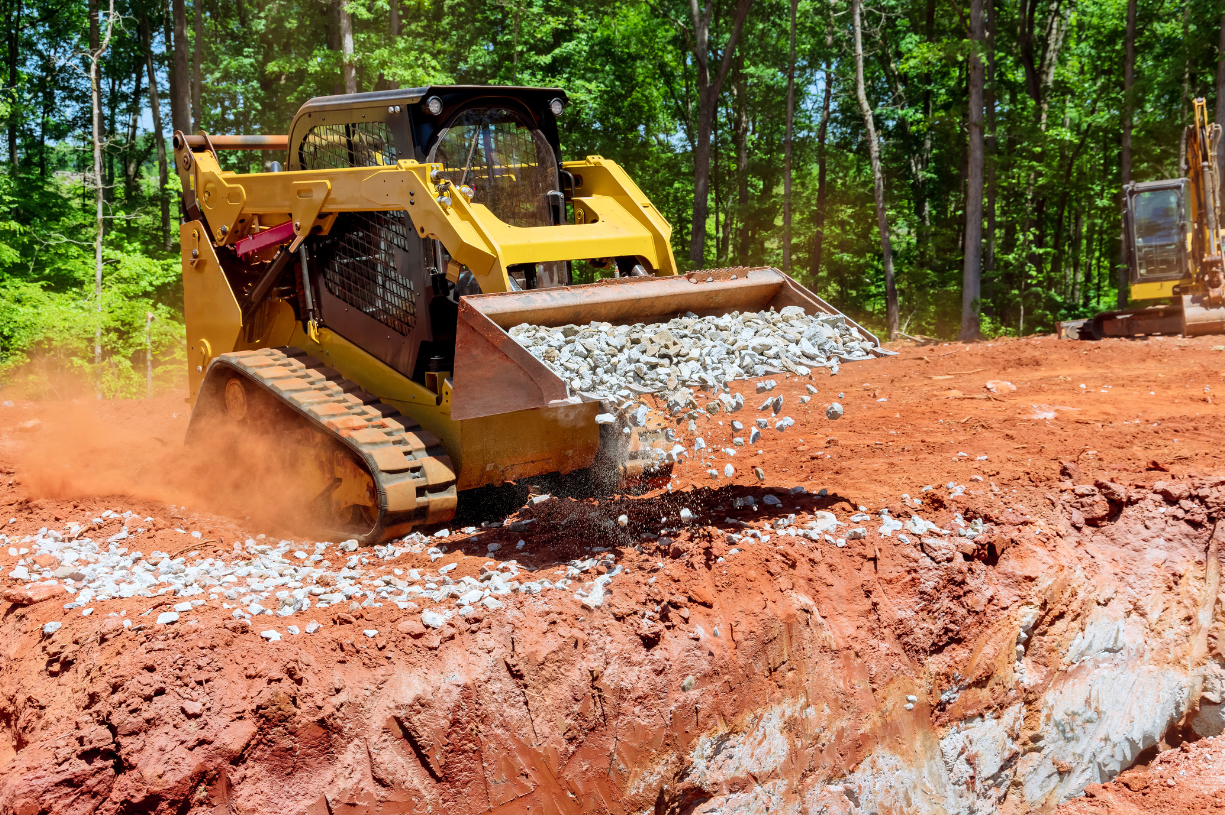 a yellow bulldozer is dumping rocks into a hole