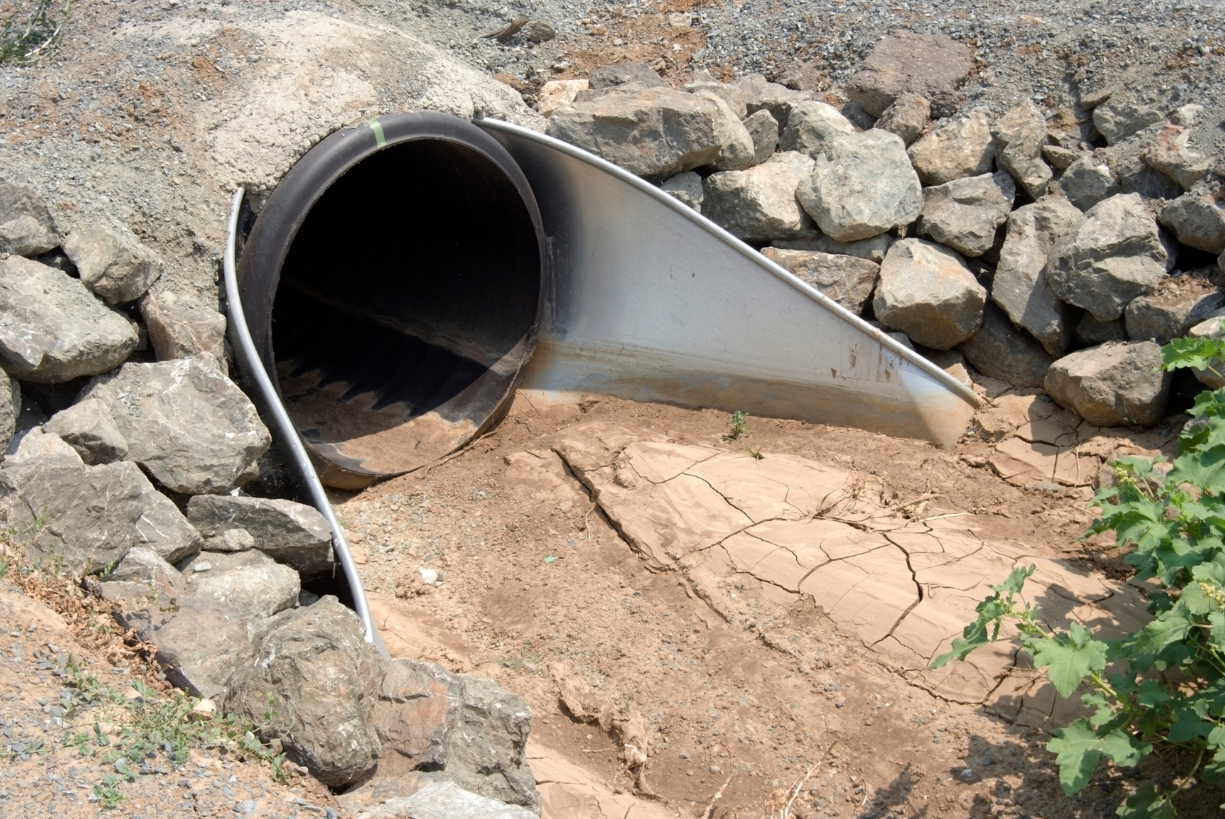 a large metal culvert is surrounded by rocks and dirt