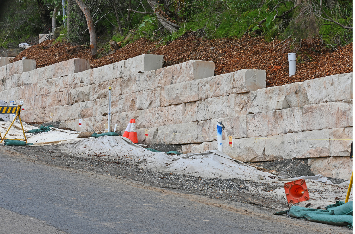a large stone wall is being built on the side of a road