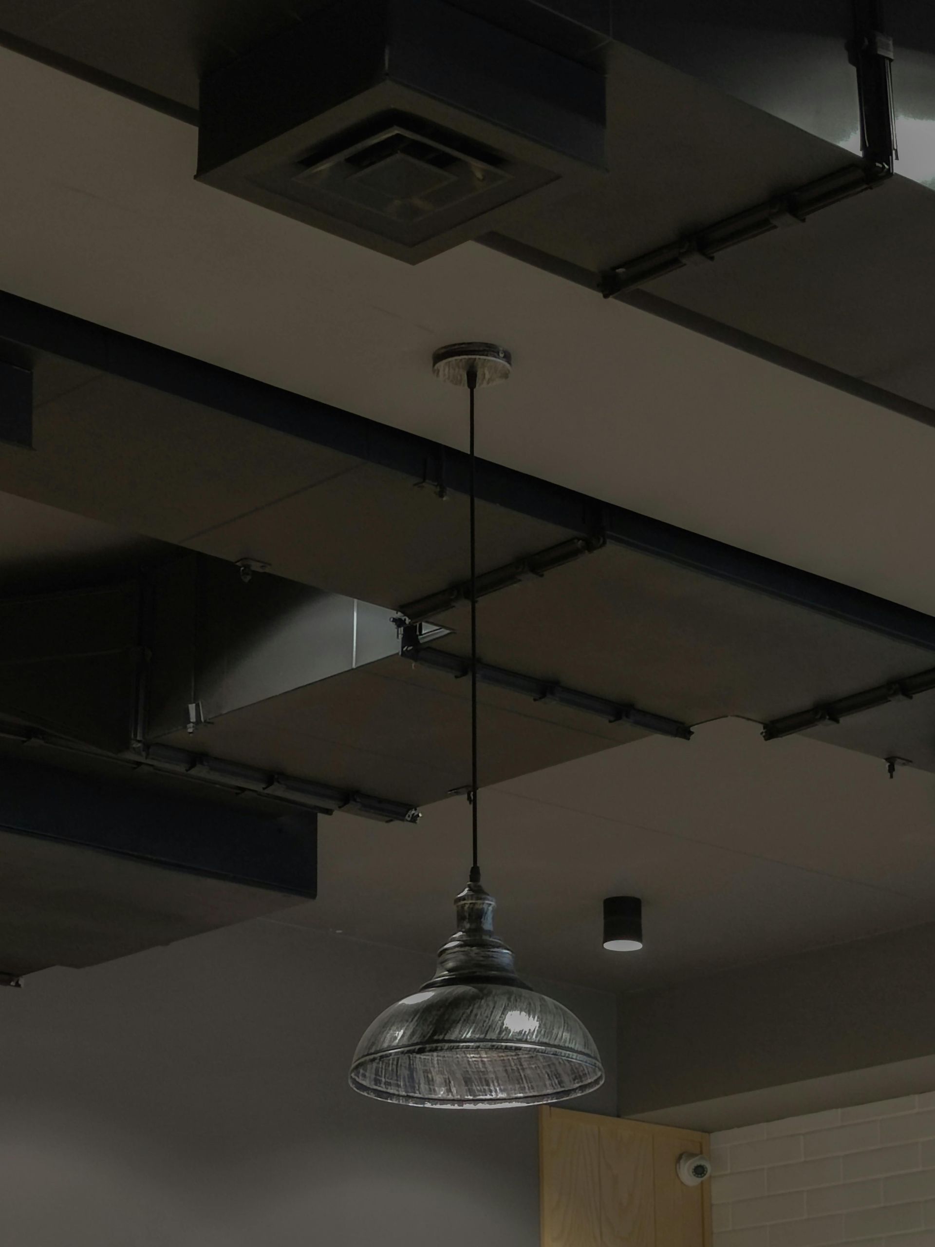 Industrial ceiling with exposed ductwork and a hanging pendant light