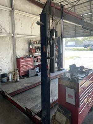 Auto repair shop with a vehicle lift and red toolboxes inside a garage