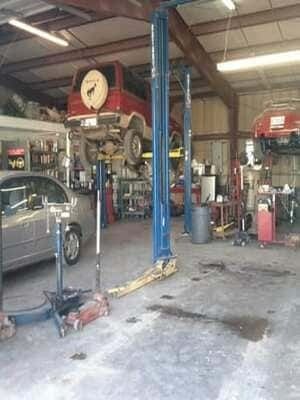Auto repair shop with car lifts, a silver car, and tools in a garage.