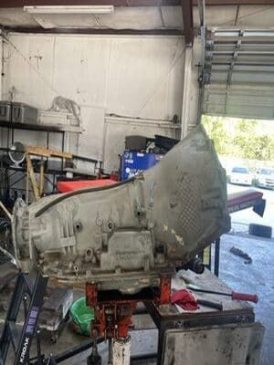 Large transmission or engine assembly on a red stand in a cluttered workshop garage