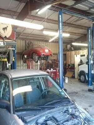 Auto repair shop with cars on lifts and a blue truck under maintenance indoors
