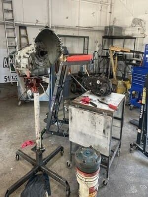 Auto repair shop with an engine on a stand beside a workbench and tools