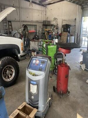 Auto shop with a tire service machine, red air compressor, and tools near a white truck.