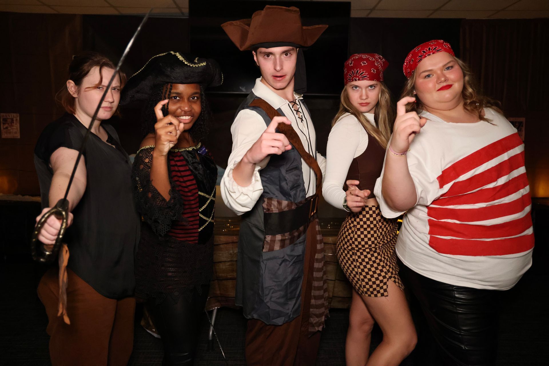 Five people in costumes posing at a party, including a cowboy and a red-striped shirt.