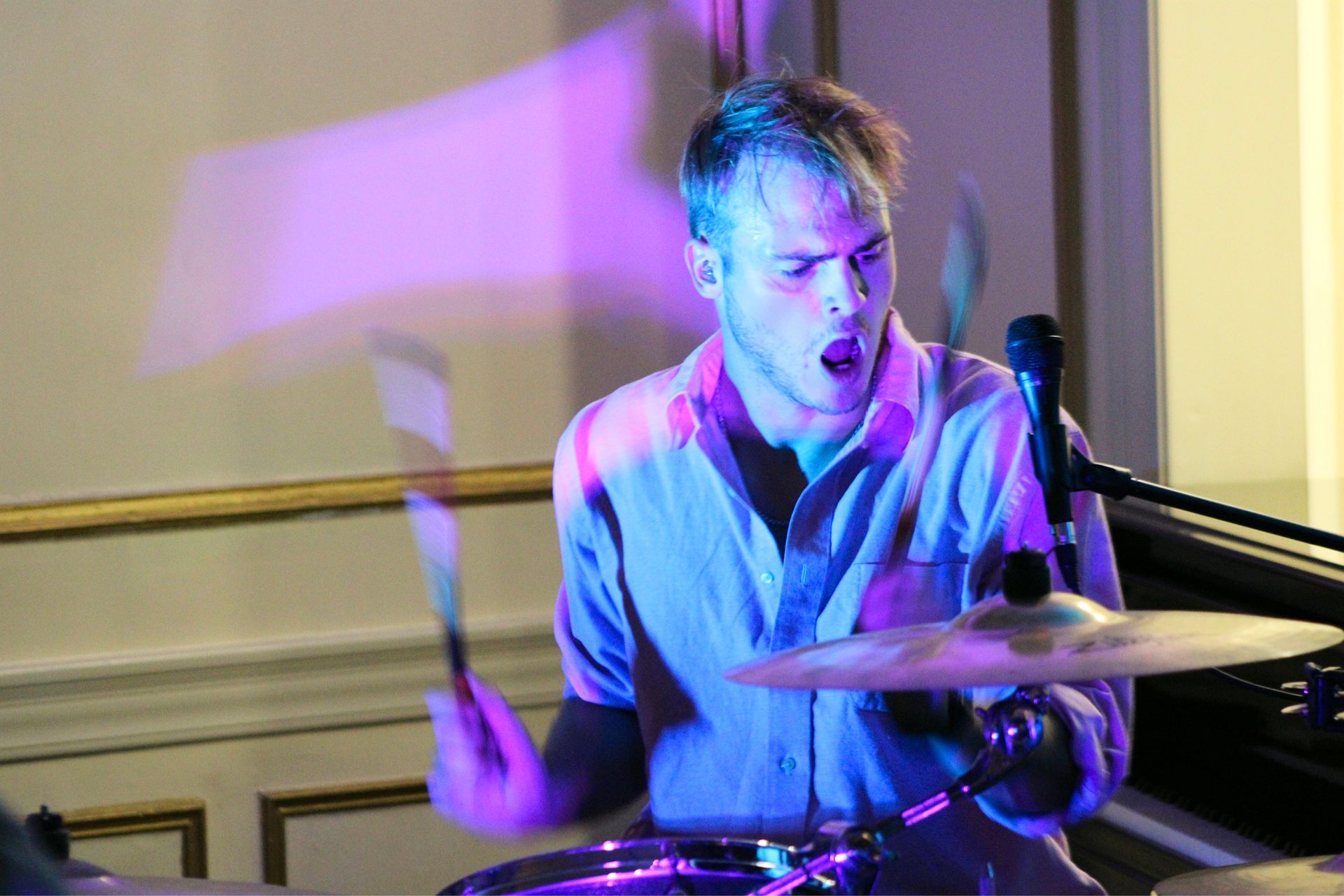 Drummer playing on stage under blue and purple lighting