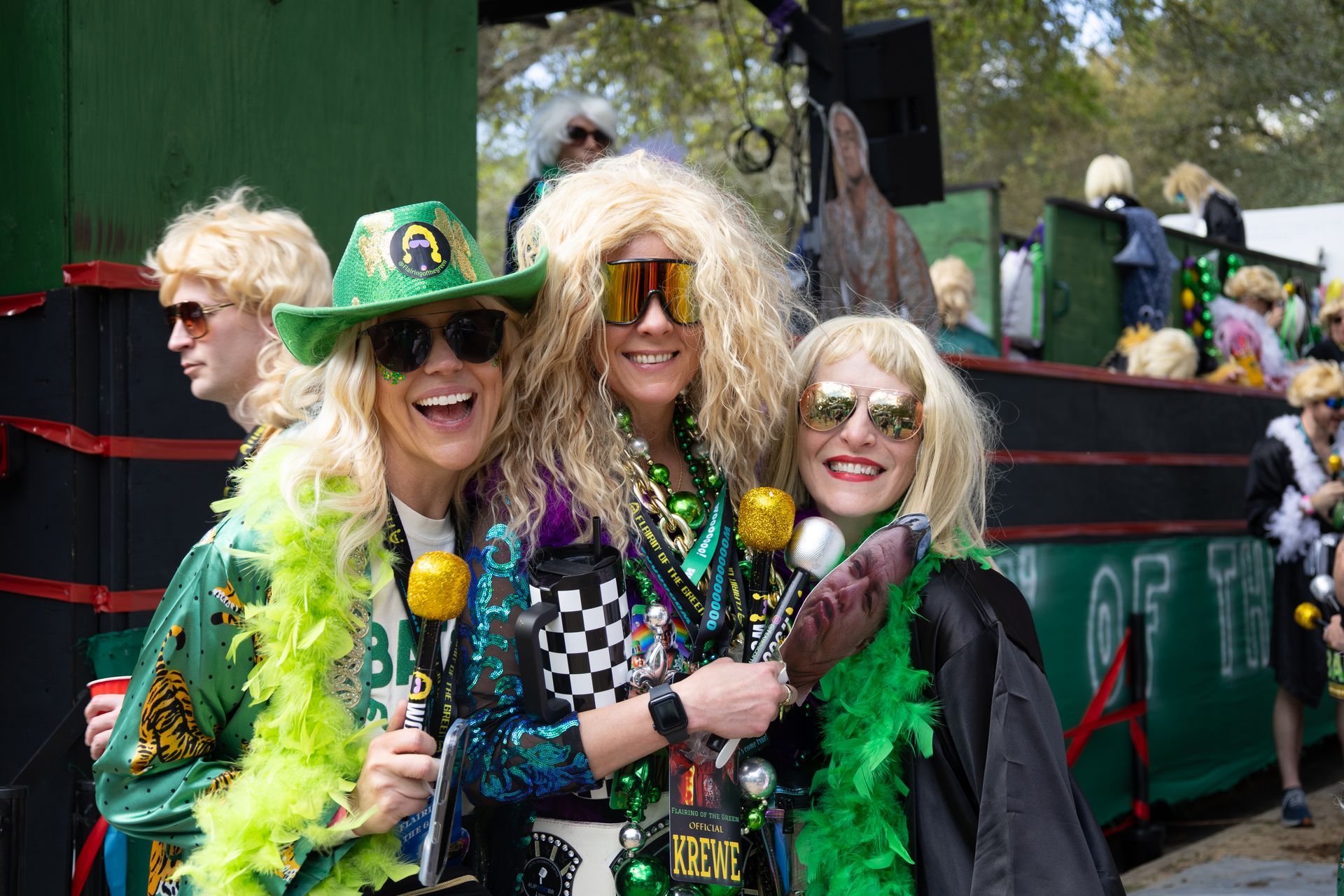 Four people in green St. Patrick’s Day outfits smiling on a parade float