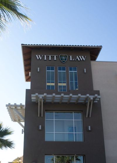 Witt Law office building with dark facade, large windows, and a blue sky above