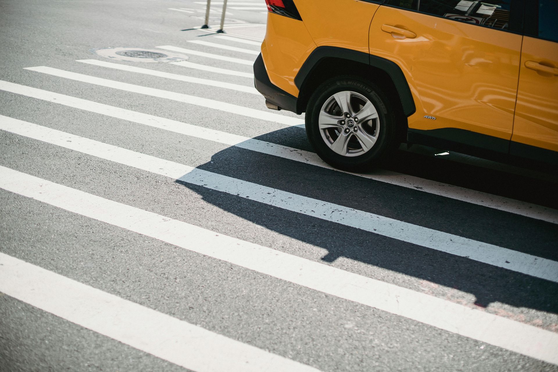 Yellow SUV at a crosswalk, with white zebra stripes on the road.