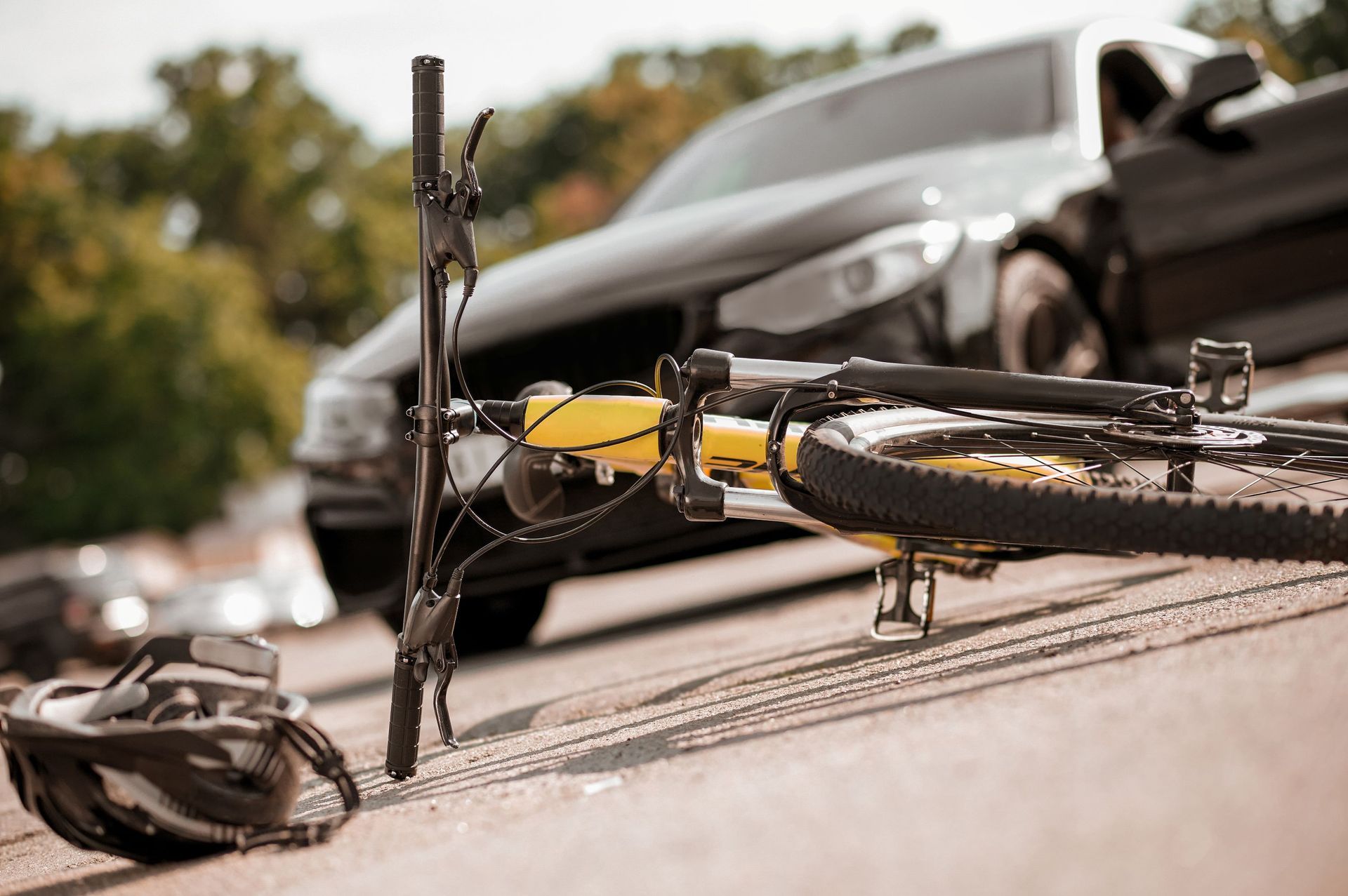Broken bicycle on road beside a damaged car after a collision