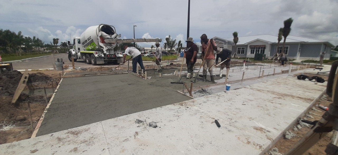 A group of construction workers are working on a sidewalk.
