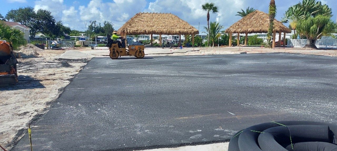 A tractor is rolling asphalt in a parking lot.