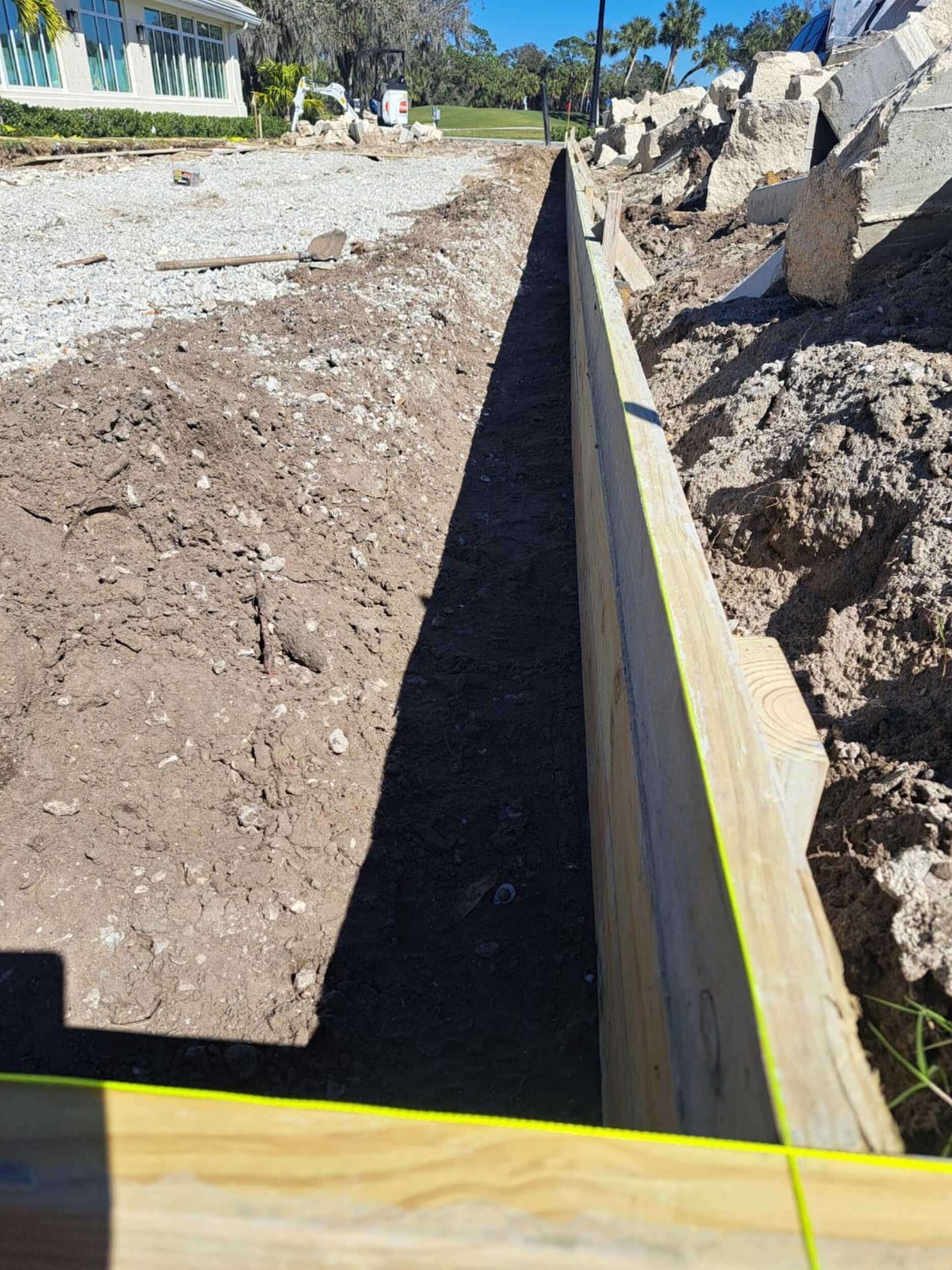 A wooden fence is being built next to a dirt road.