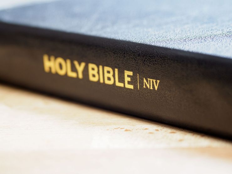 Close-up of a black Holy Bible NIV with gold lettering on a light surface