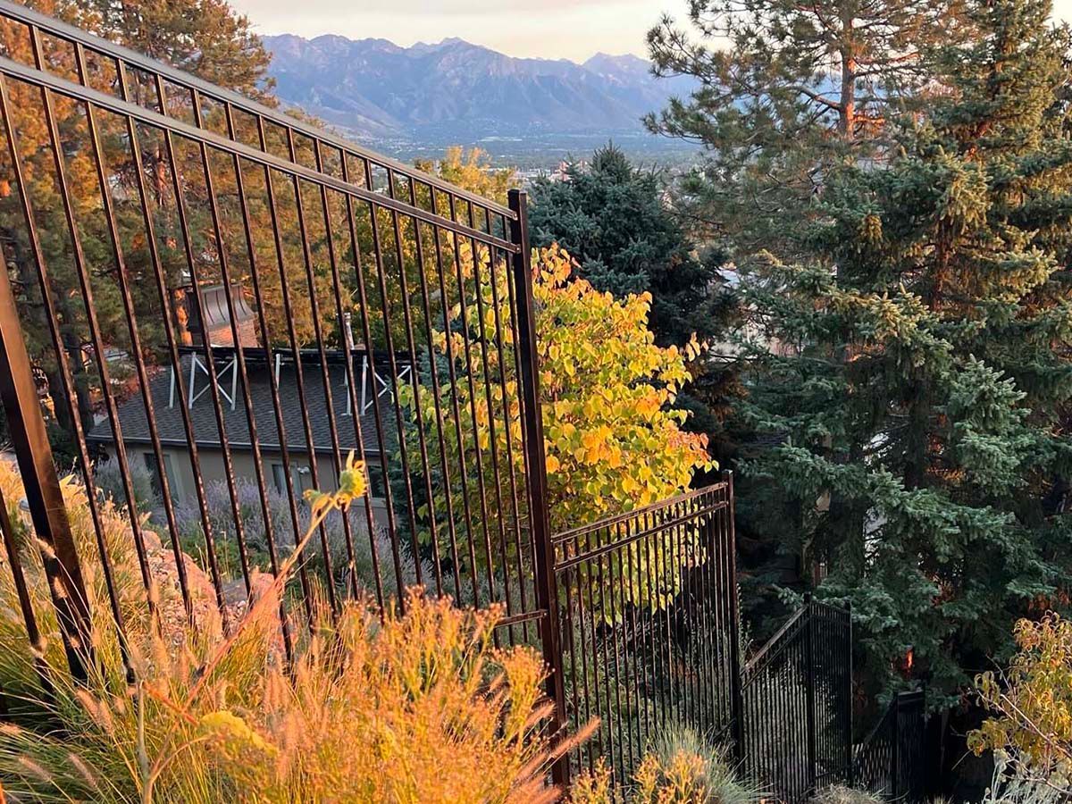 Autumn hillside with black fence, colorful trees, and mountains in the distance