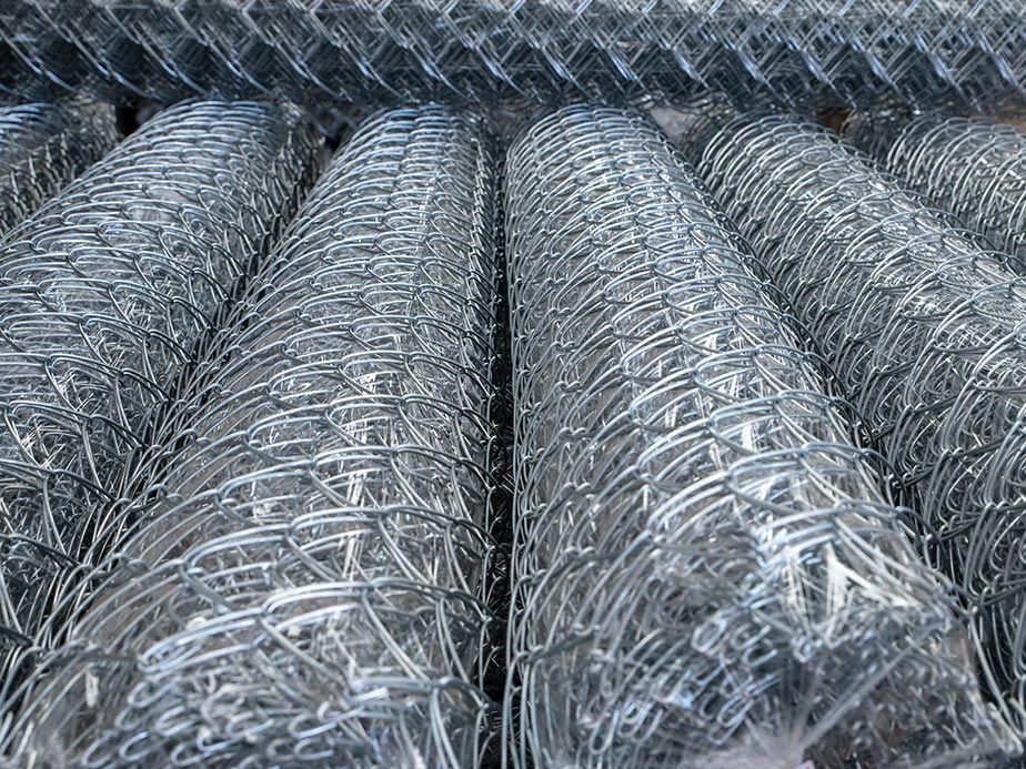Coils of silver chain-link fencing stacked in rows