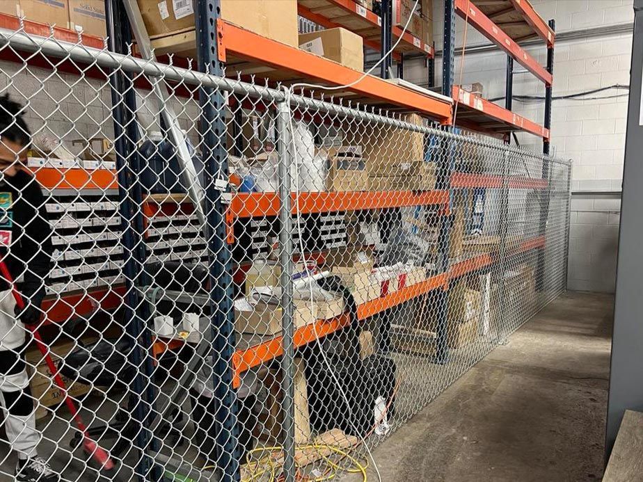 Industrial storage racks behind chain-link fencing in a warehouse aisle