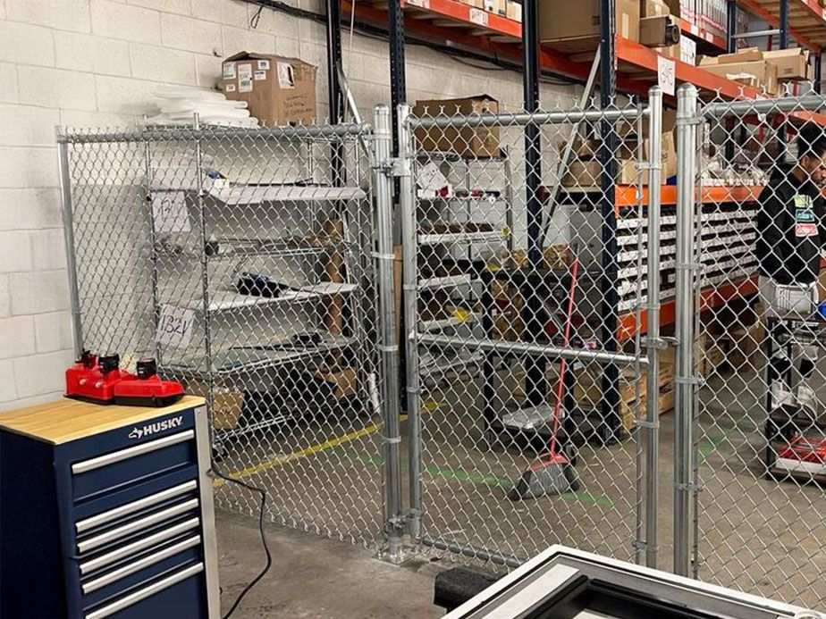 Industrial warehouse with chain-link fence, shelving, and a blue tool chest in the foreground