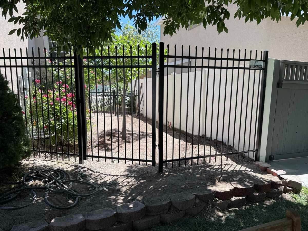 Brown metal driveway gate with vertical bars and square posts