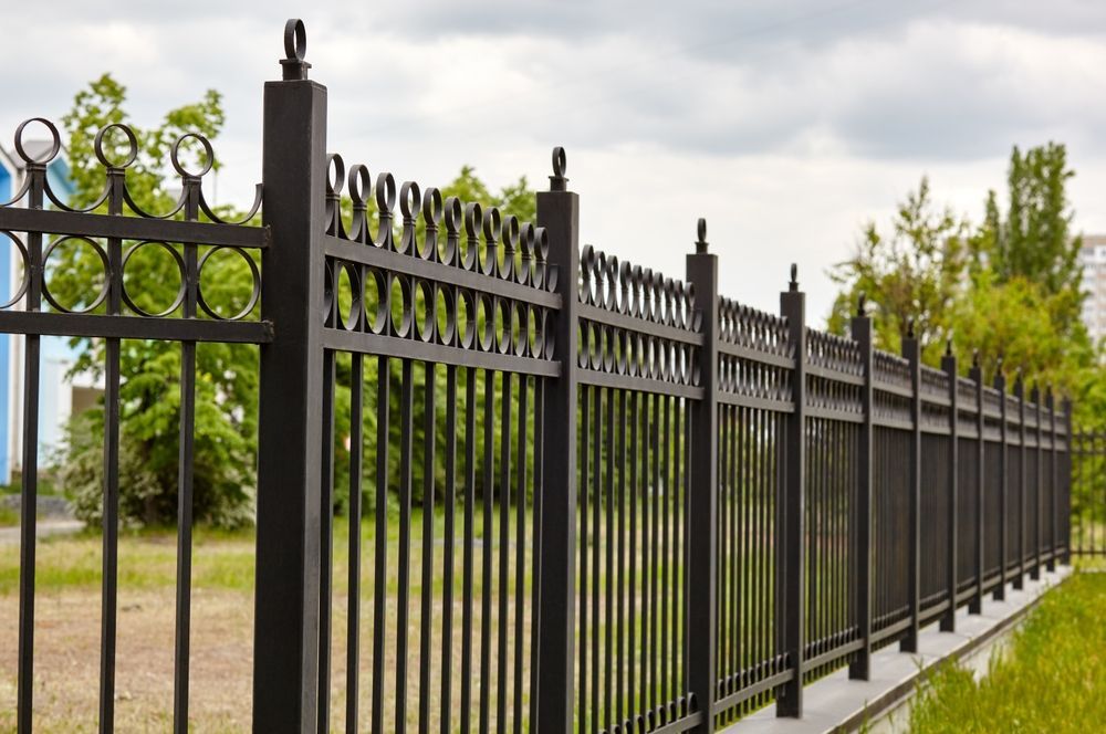 Black wrought-iron fence with decorative scrollwork, forming a corner enclosure on a white background