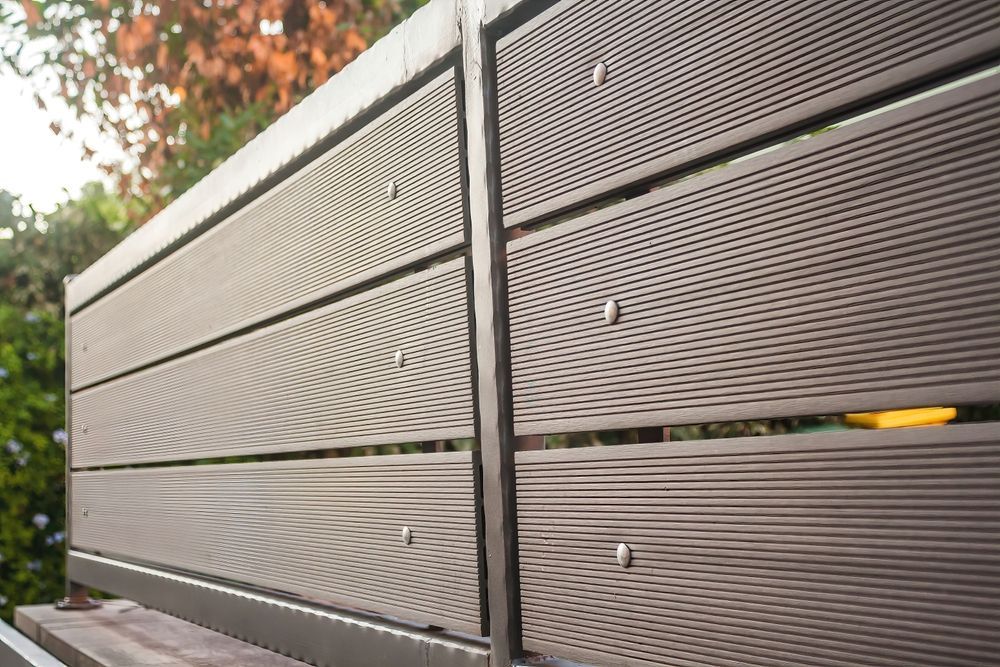 Close-up of a gray slatted outdoor fence with a narrow yellow object peeking through the gap
