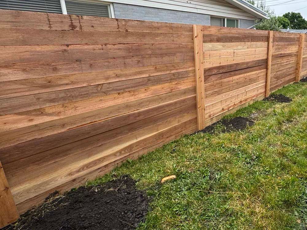 New wooden privacy fence with horizontal planks along a grassy yard