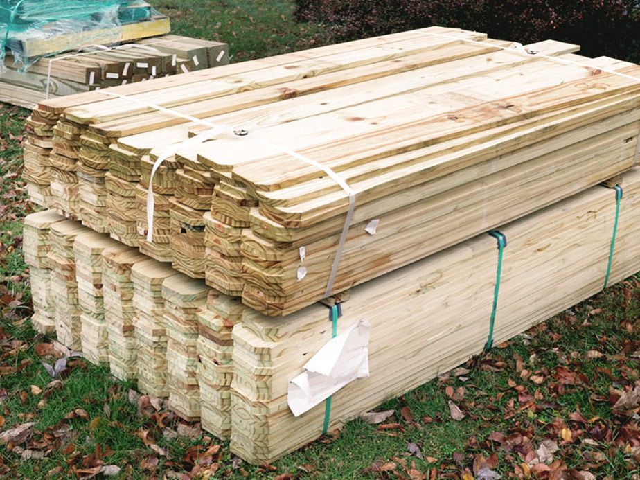 Stacked lumber boards bundled outdoors on grass