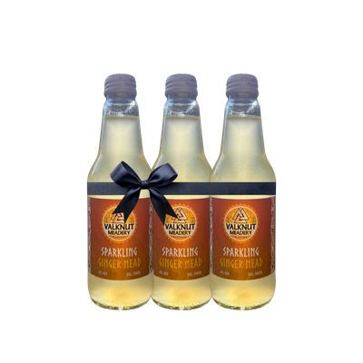 Three bottles of sparkling ginger mead tied with a black bow.