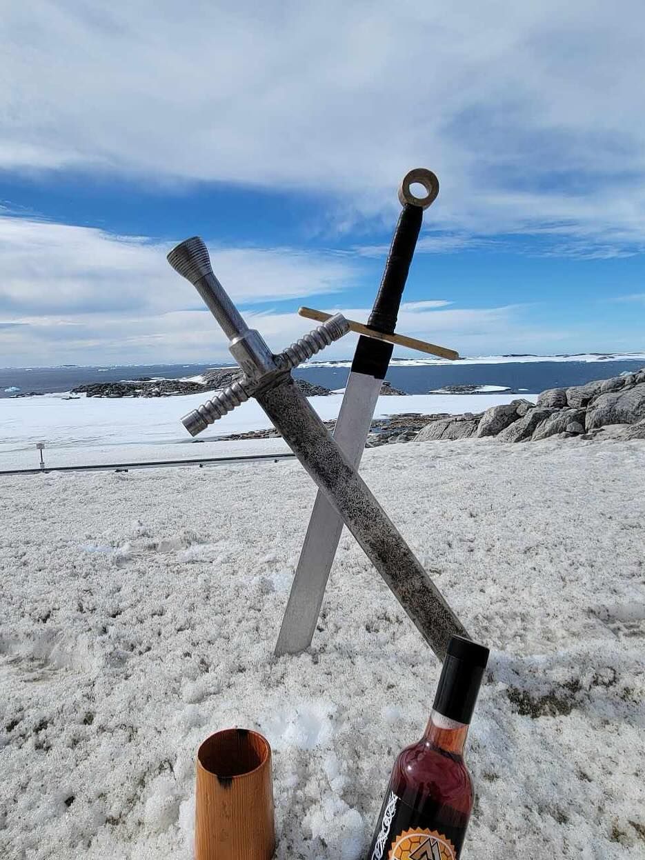 Two swords and a bottles of honey wine are sitting in the snow.