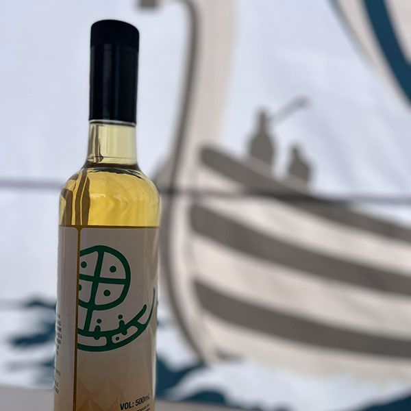 A bottle of alcohol with a green sunwheel petroglyph on the label