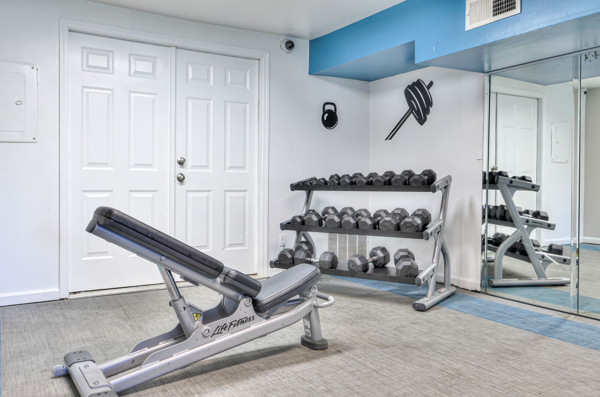 Photo of the gym, showing a workout bench and dumbbells