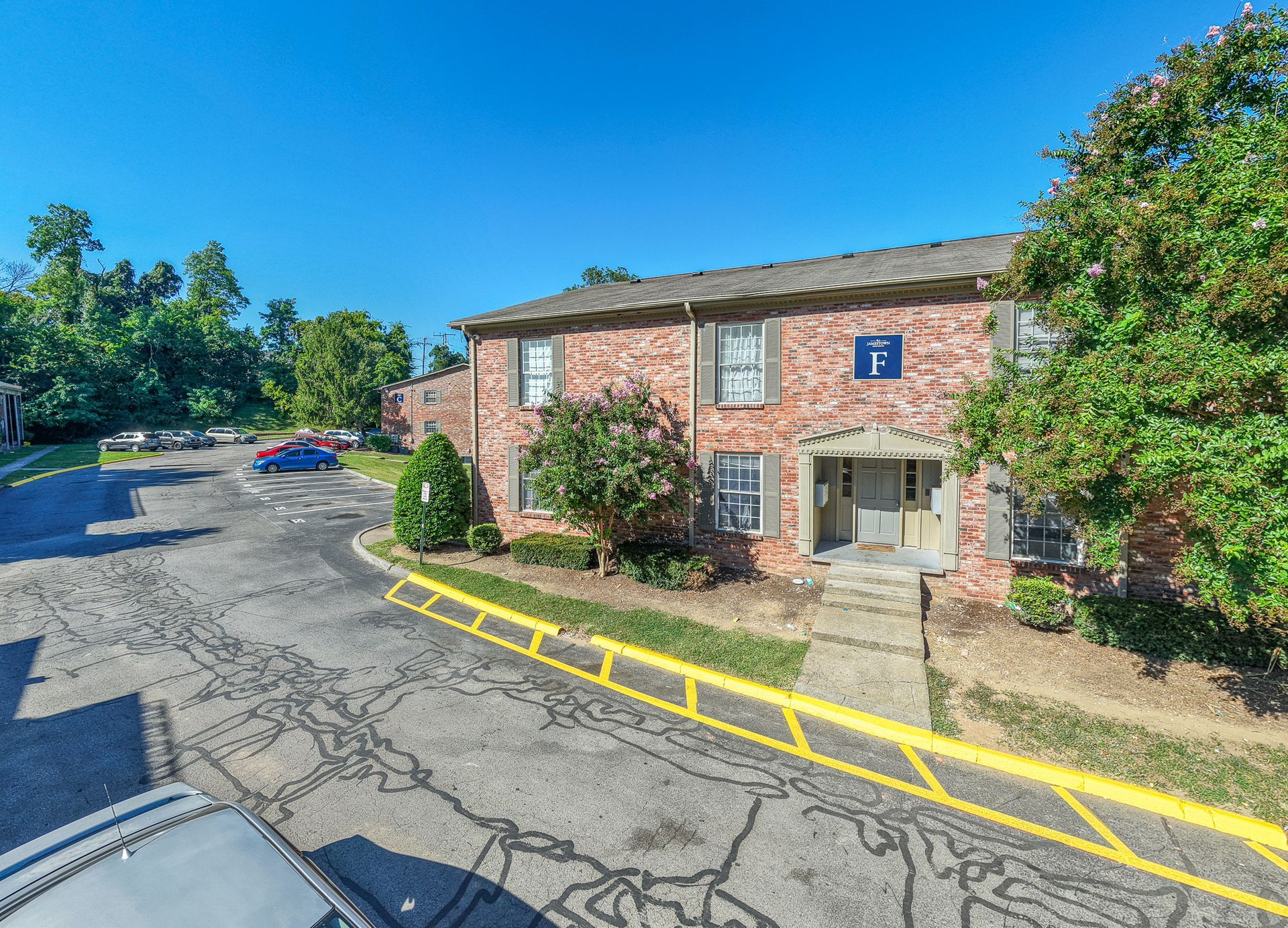 Photo of a two-story, red brick building with a parking lot in front and next to the building