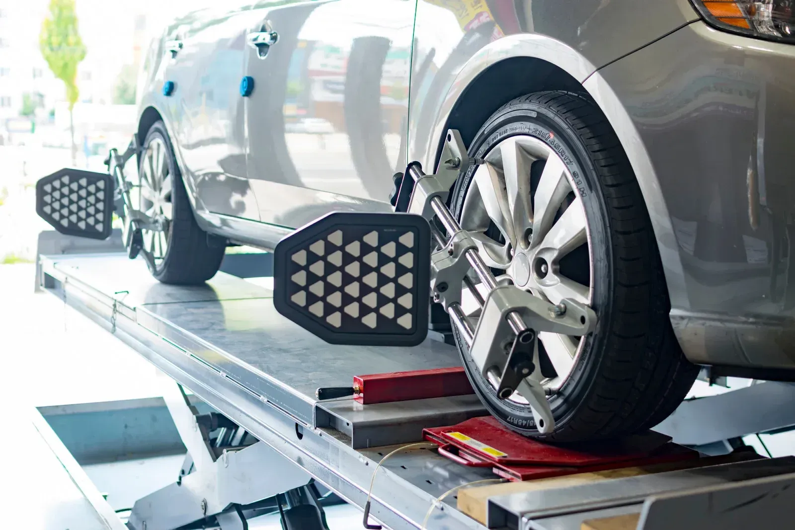 Car being aligned on a lift with gauges attached to the wheels.