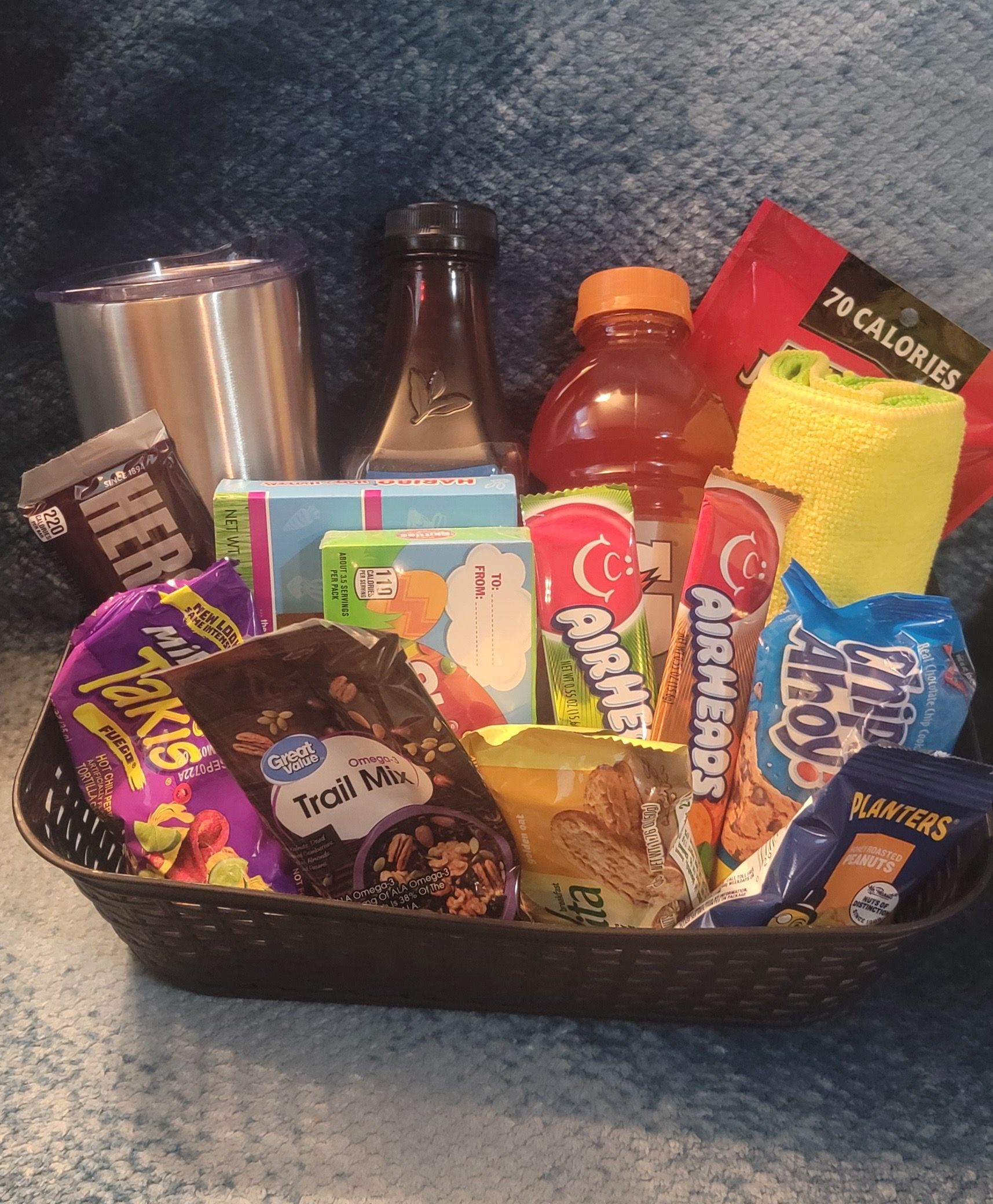 Assorted snacks and drinks packed in a black basket on a table.