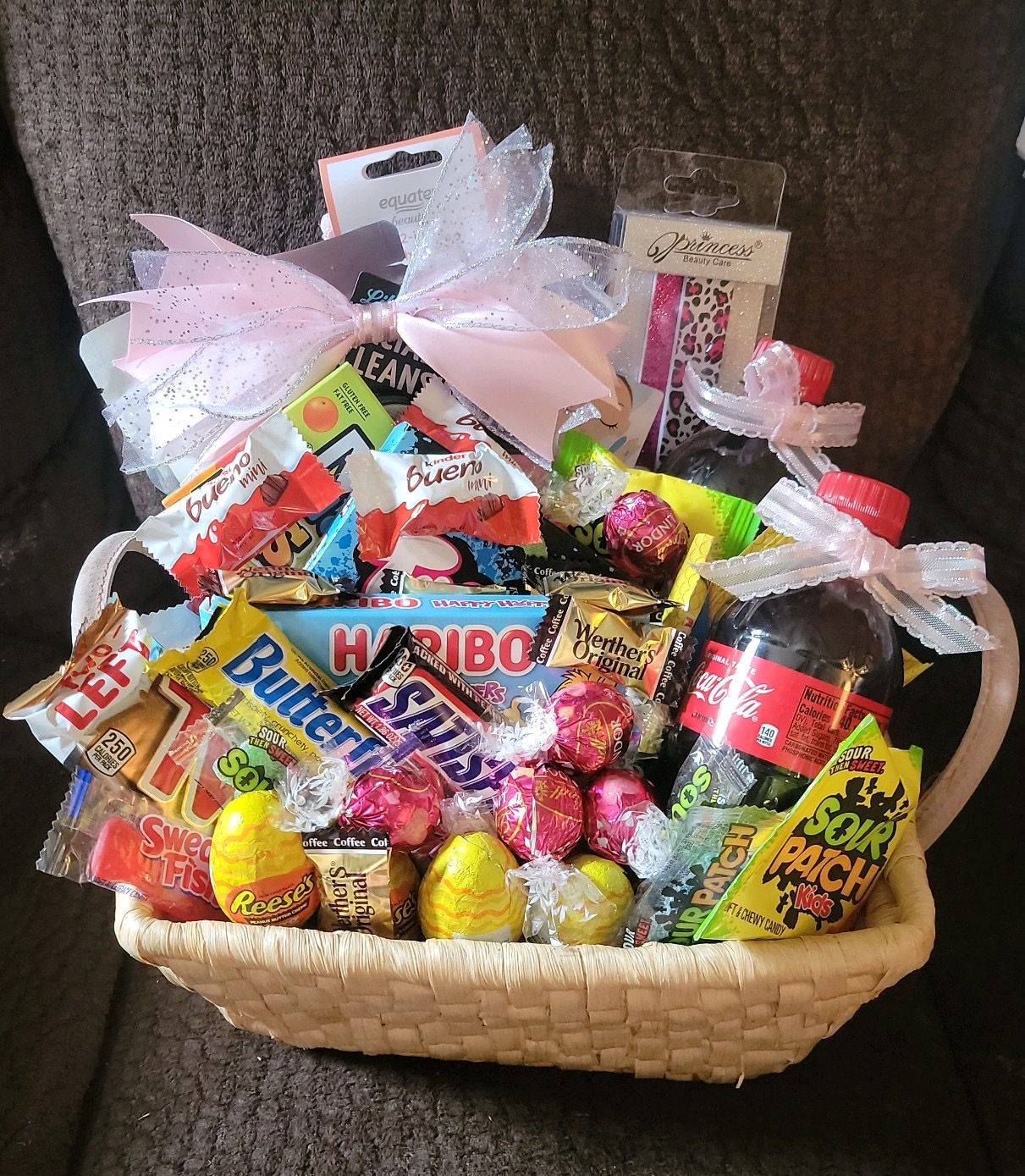 Basket of assorted colorful candy and chocolates in clear treat bags with bows on a couch