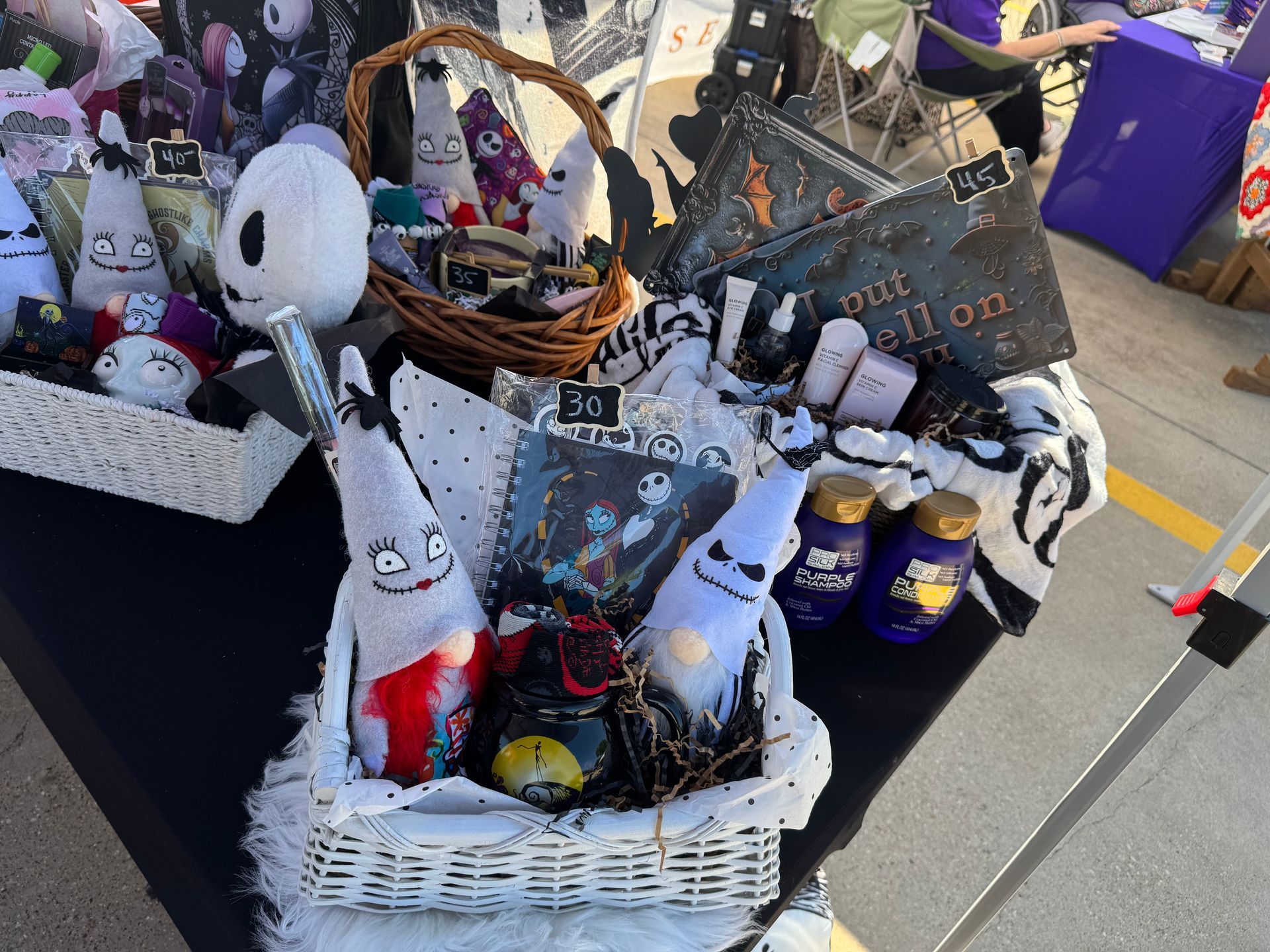 Halloween gift baskets with spooky toys and treats on a black table outdoors