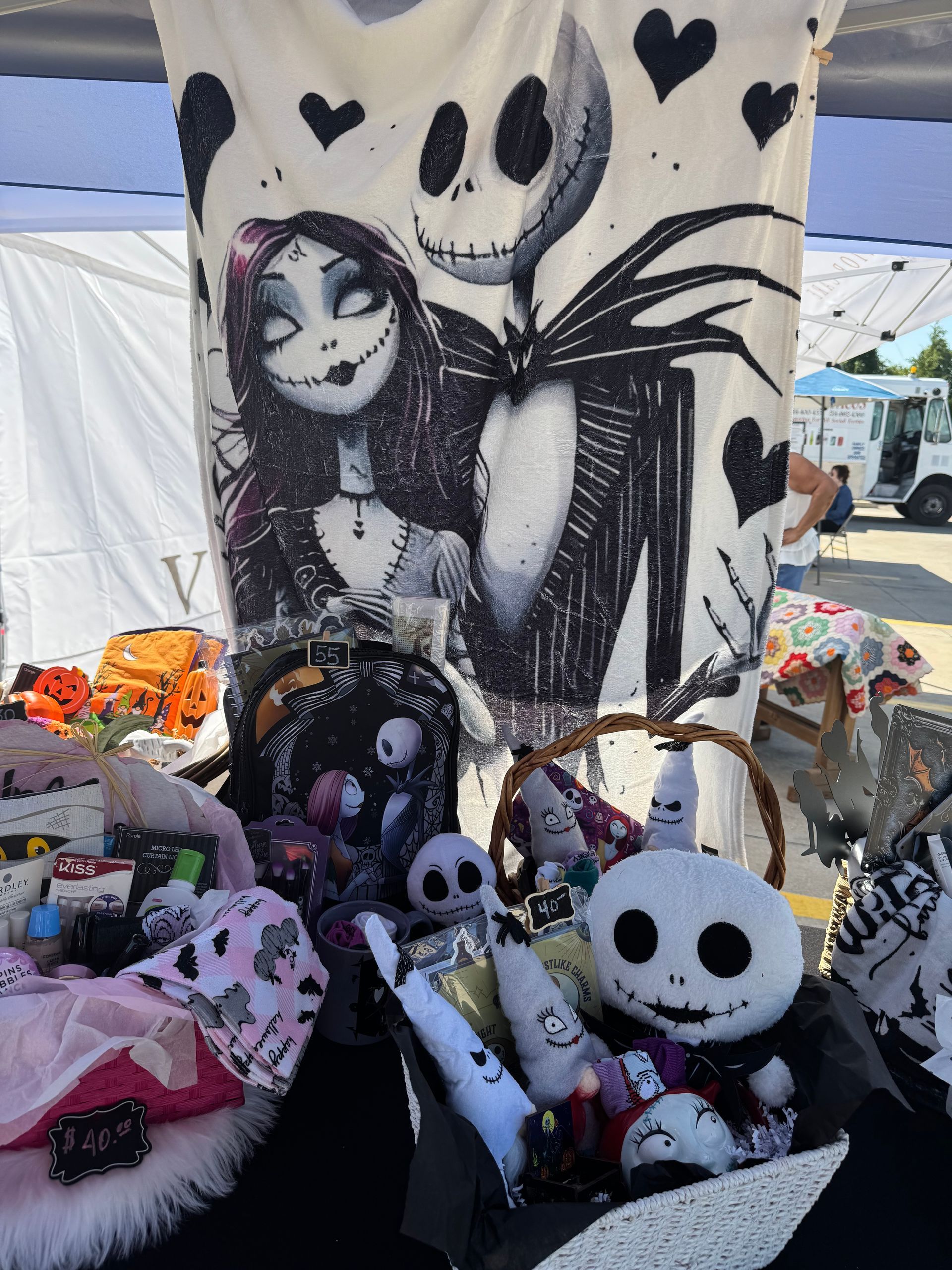 Halloween-themed display of stuffed dolls and skulls in a black-and-white booth setup with heart decorations