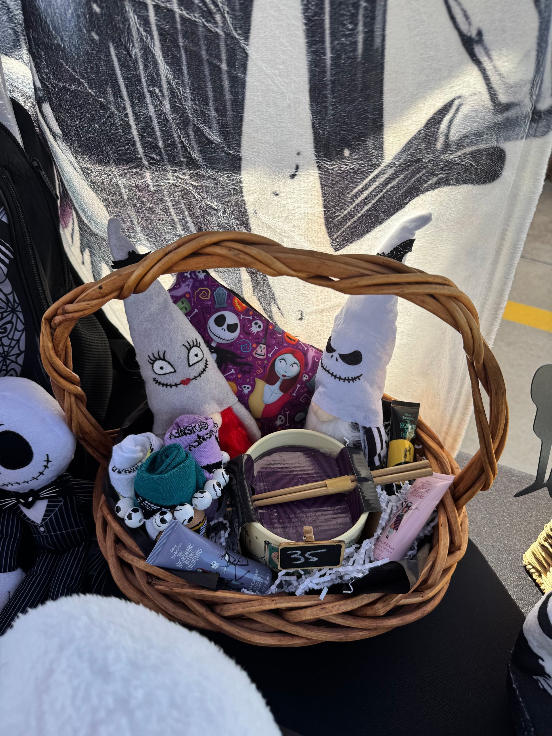 Basket of Halloween plush toys and decorations on a chair, including ghosts, a skull, and a pumpkin bag