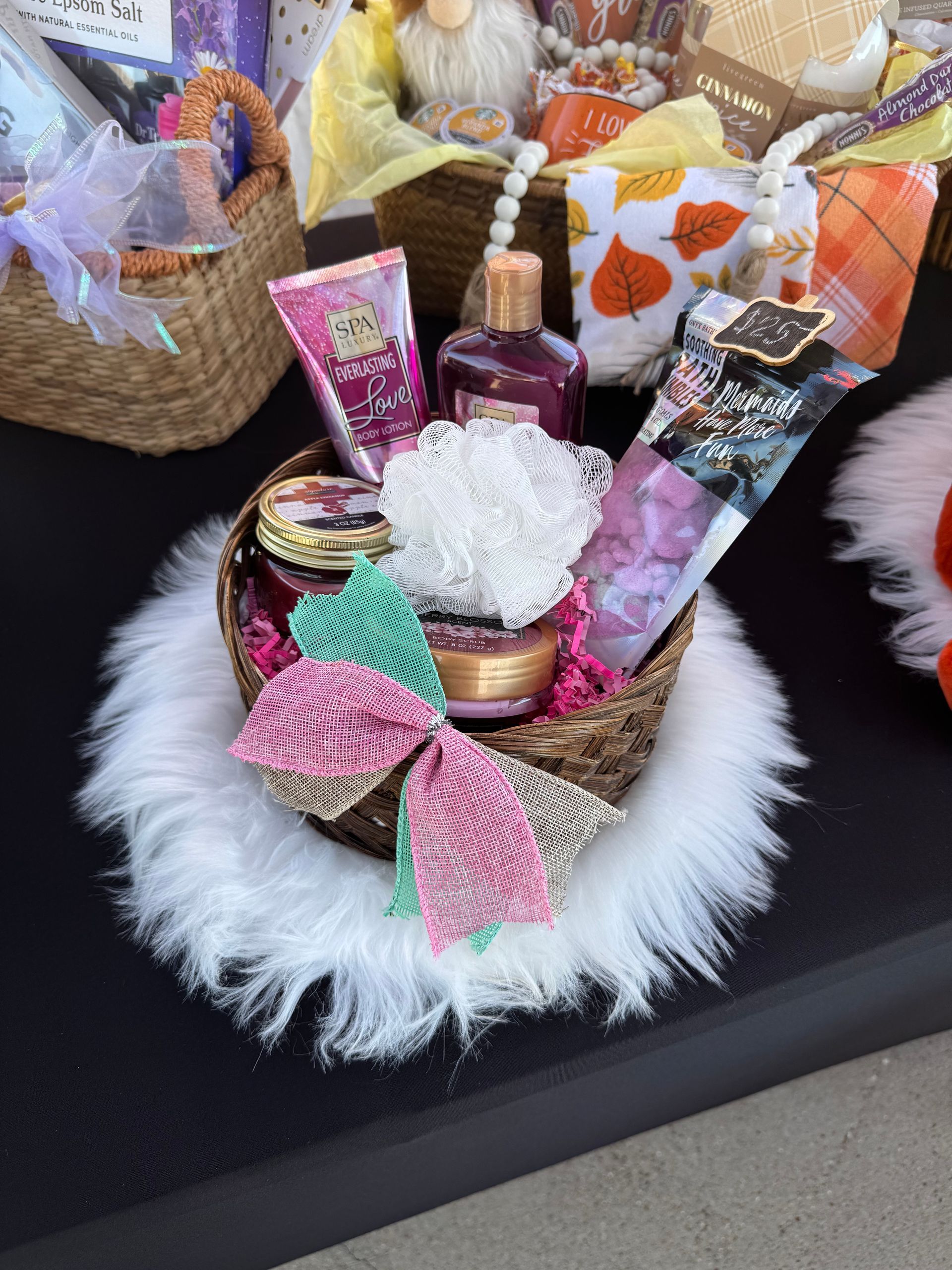 Spa gift basket with lotion, bath items, and a pink bow on black fur trim