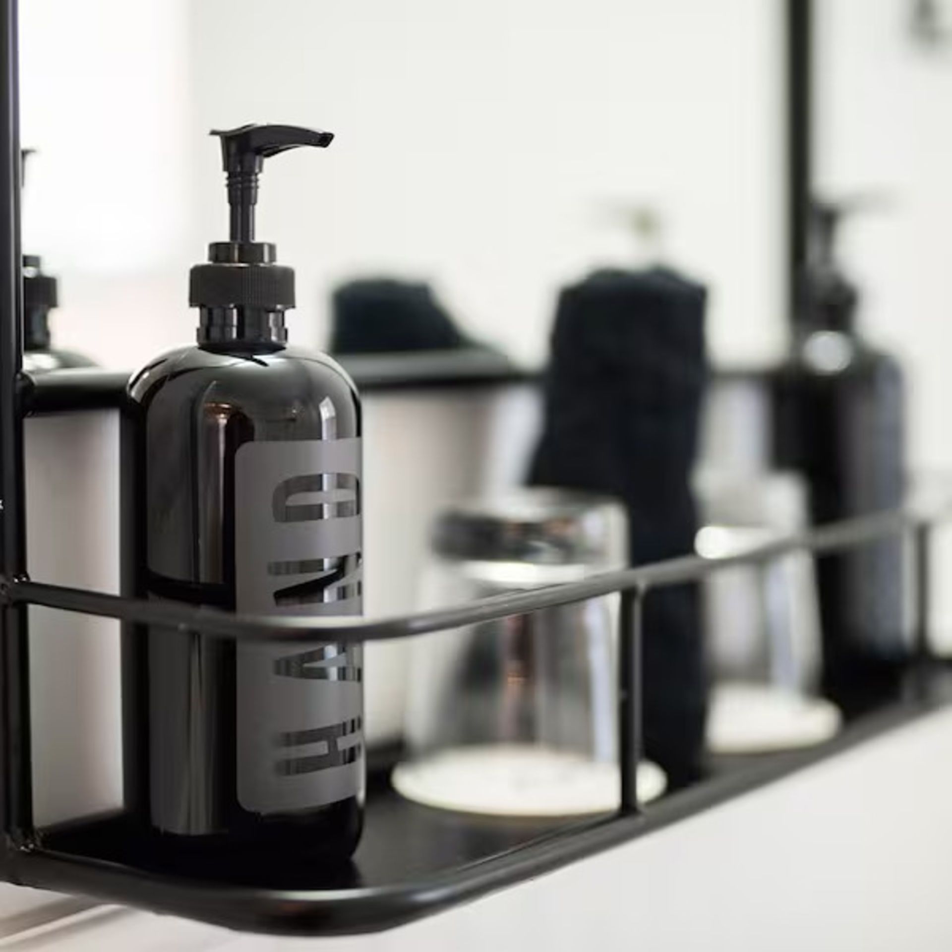 Black hand soap dispenser on a shelf in a bathroom.