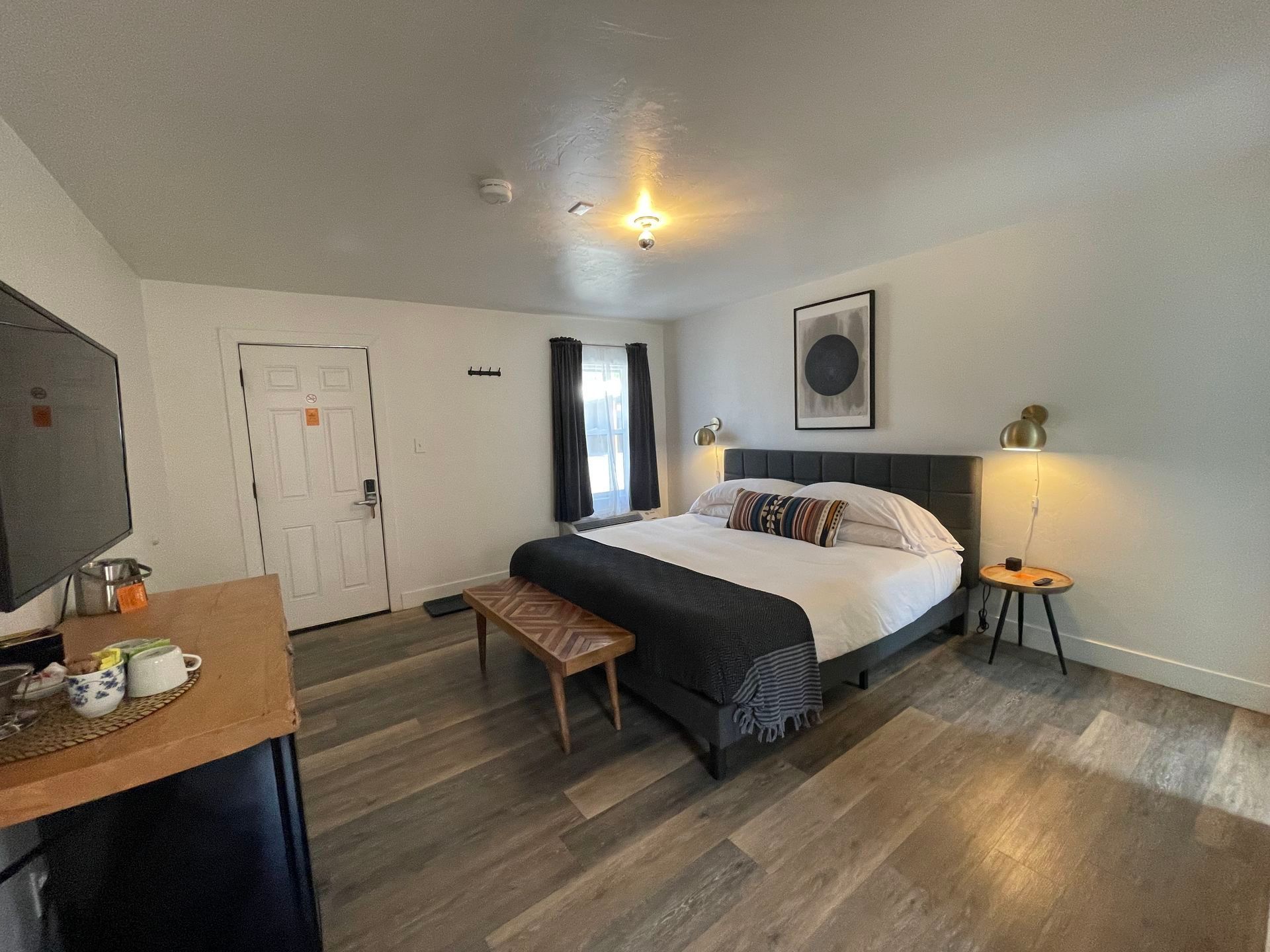 Bedroom with a bed, nightstands, TV, and wood-look flooring.