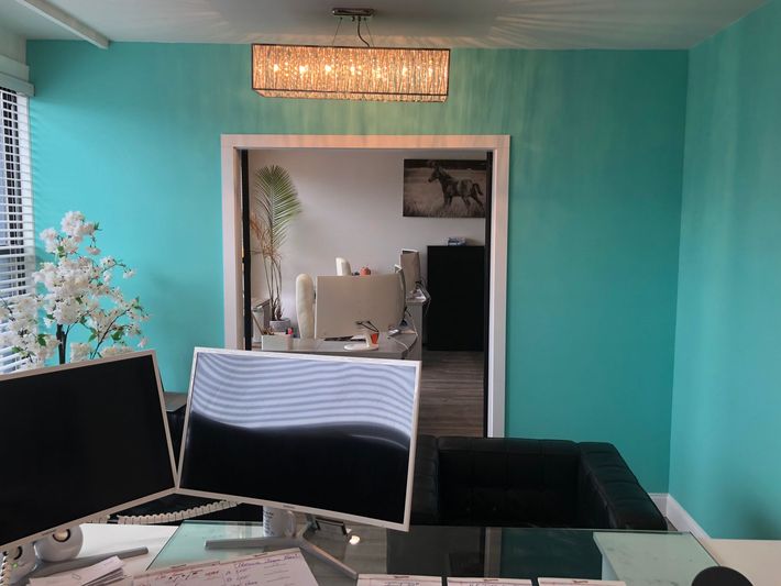Turquoise room with desk and computer monitors, looking into a mirrored doorway and adjoining room