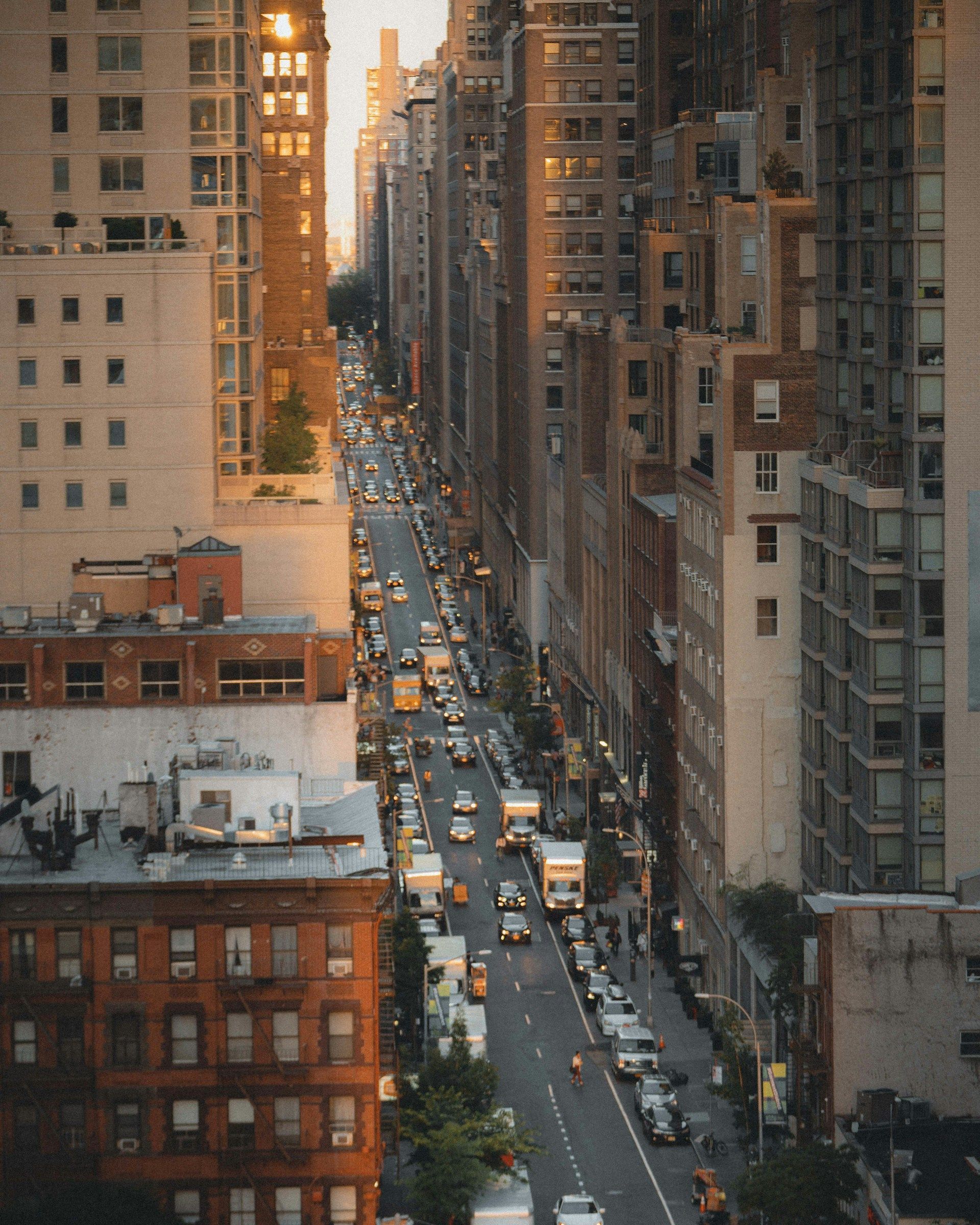 Aerial view of a busy city street lined with tall buildings at sunset.