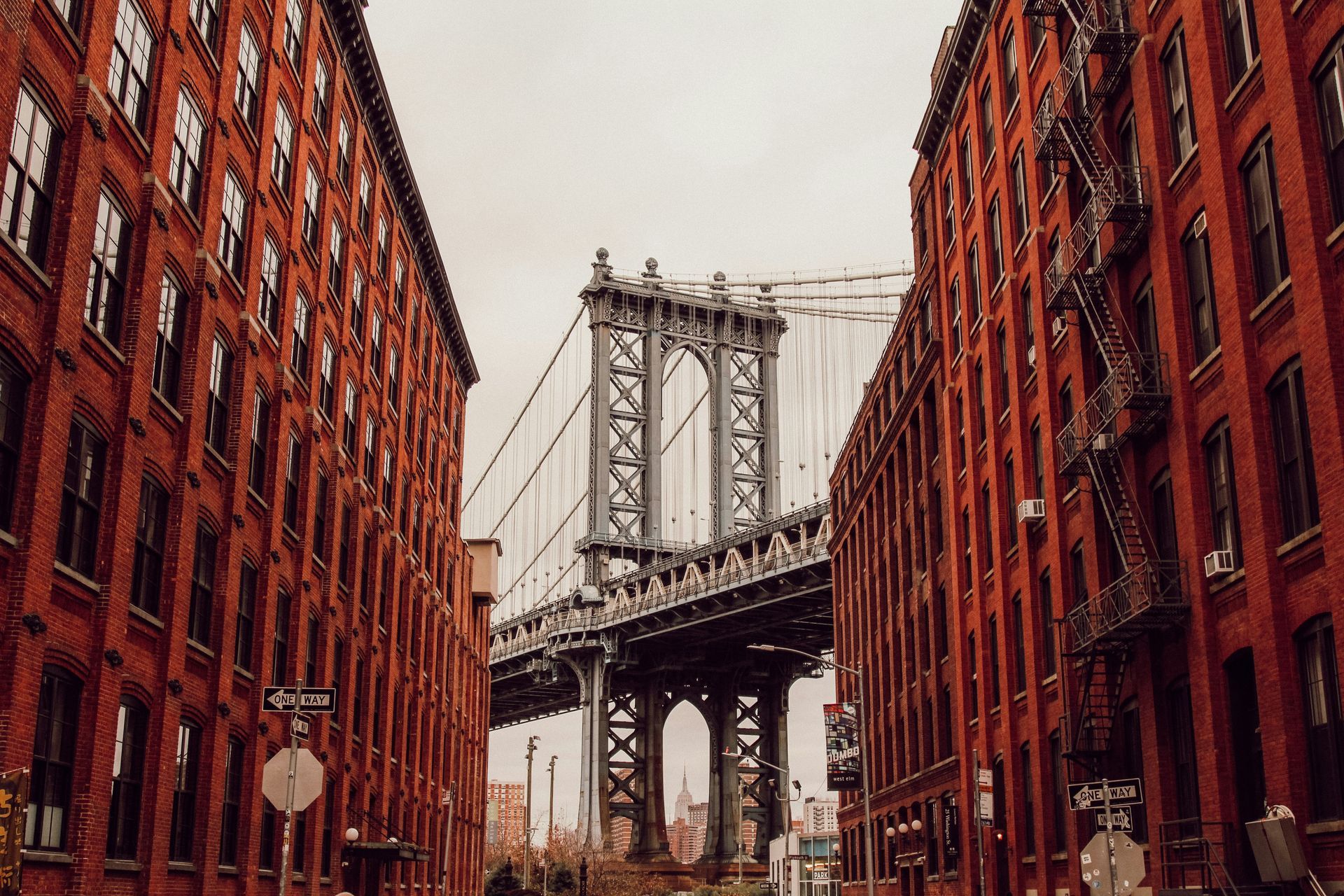 Manhattan Bridge framed by red brick buildings in a city street view