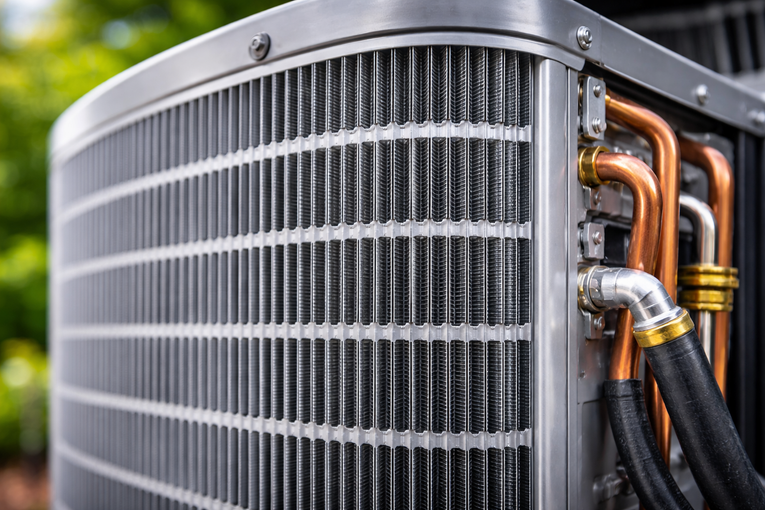 Close-up of an air conditioner unit with metal fins and copper pipes.