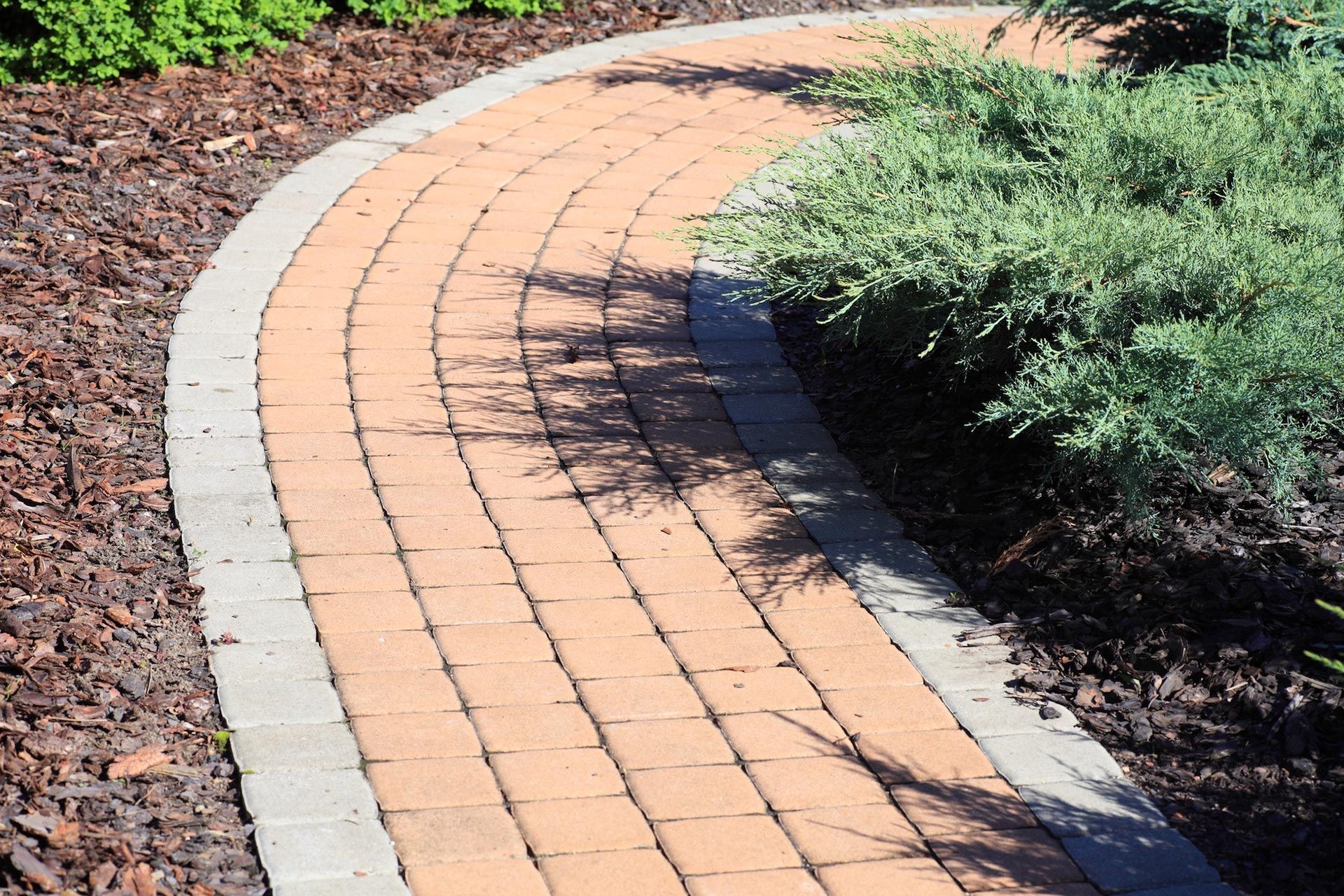 Curved tan brick paver walkway with stone border edging for paver walkways installation in West Melbourne FL