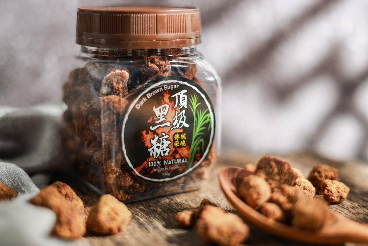 一罐紅糖塊，一把木勺，還有一些紅糖塊散落在木質表面上。