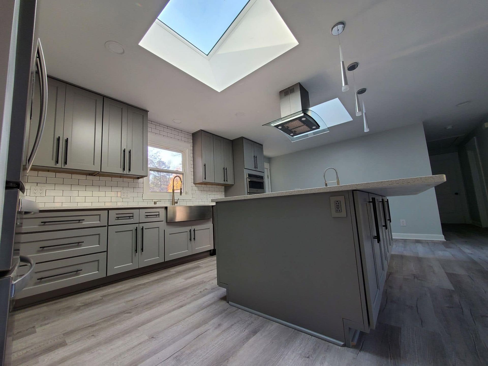 Modern gray kitchen with island, skylights, and wood-look flooring